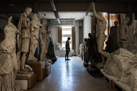 zur Vergrößerungsansicht des Bildes: Studentin in der Gipsabguss-Sammlung am Ende eines Ganges gesäumt von Statuen