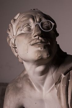 zur Vergrößerungsansicht des Bildes: Nahaufnahme einer männlichen Statue mit einer aufgesetzten Brille