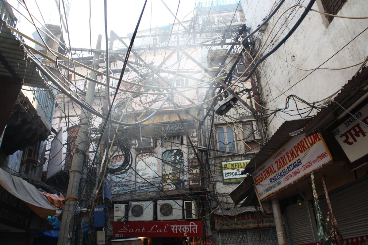 enlarge the image: Many intersecting power lines in a backyard in Old Delhi, India, 2013, photo by Ira Sarma.