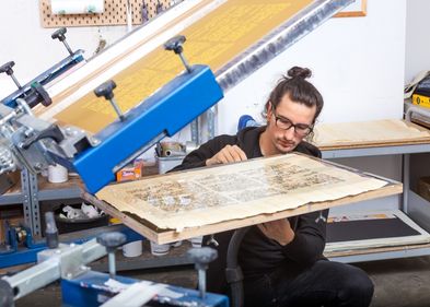Dennis Blumenstein bei der aufwändigen Herstellung der Replik des Papyrus Ebers per Siebdruckverfahren in der Leipziger Werkstatt von Schmidt, Blumenstein GbR.