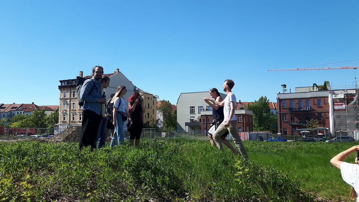 Menschen in tanzender Bewegung auf einer grünen Wiese des Jahrhundertfelds in Leipzig