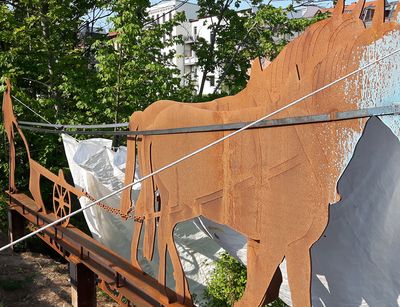 Kunstinstallation aus Metall, die die Silouette zweier Pferde, eines Pfluges und eines Mannes zeigt