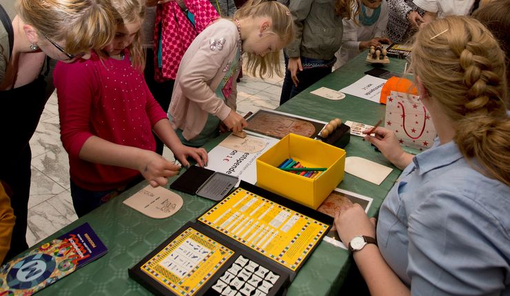 Kinder vor einem Tisch, darauf Bastelmaterialien zum Thema Hieroglyphen