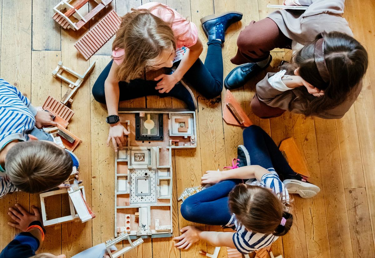 zur Vergrößerungsansicht des Bildes: Kinder sitzen um ein Holzmodell einer römischen Villa herum und betrachten die einzelnen Teile.