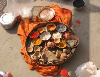 Metallschalen mit verschiedenfarbigen Pulvern und Gewürzen auf einem Holztablett, das auf einem orangefarbenen Tuch auf dem Steinfußboden steht, das sind Untensilien für das hinduistische Totenritual Shraddha, Varanasi, Indien, 2011, Foto: Johanna Buß