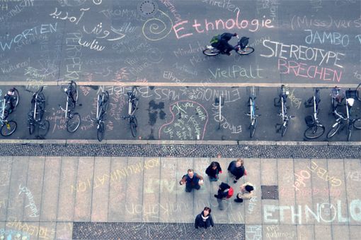 Auf der Straße sind mit Kreide Begriffe gemalt, Studierende stehen daneben, Institut für Ethnologie Leipzig