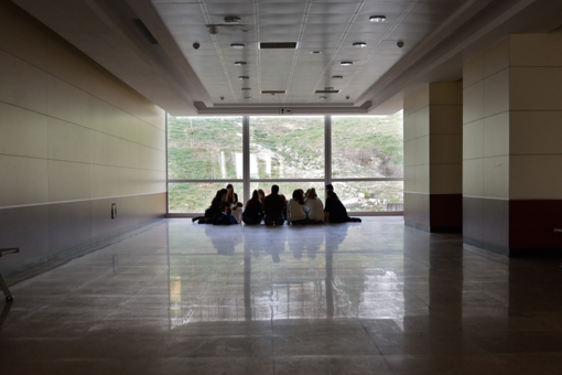 Studierende sitzen auf dem Boden im Hörsaalgebäude
