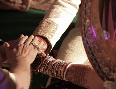 Es sind verschränkte Hände eines indischen Hochzeitspaares während der Zeremonie zu sehen. Foto: Ira Sarma