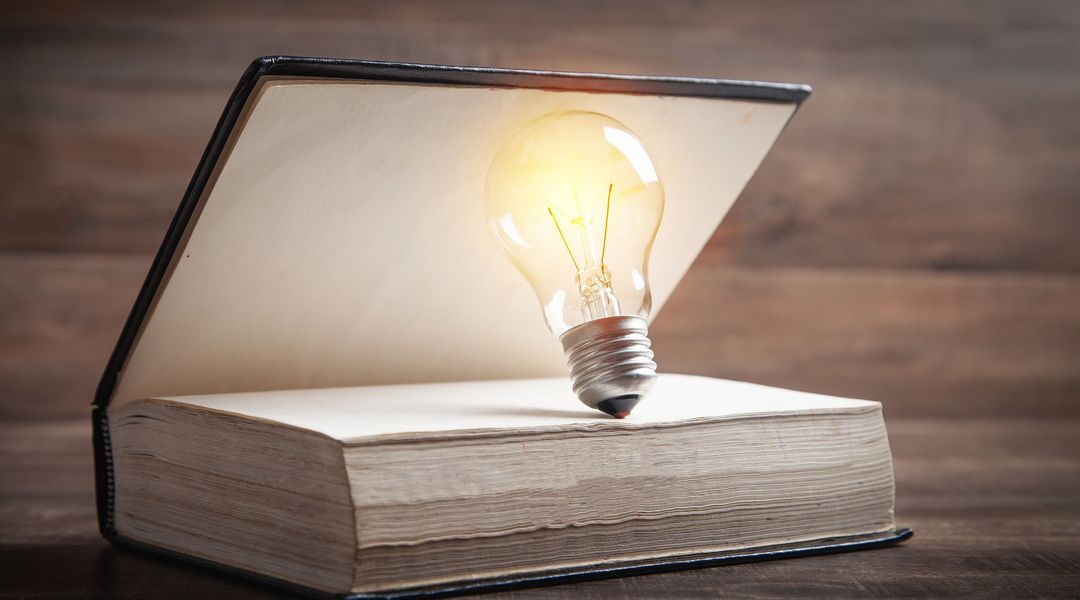 The photo features a book and a light bulb on a wooden background, photo by user #247564, ©Colourbox.