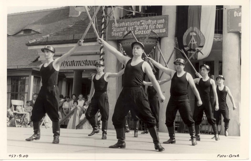 zur Vergrößerungsansicht des Bildes: Eine Gruppe männlicher Tänzer mit Helmen und Werkzeugen