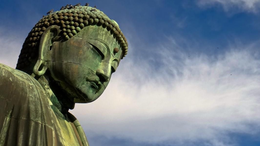vor blauem Himmel sieht man den Kopf der Großen Buddha Statue in Kamakura
