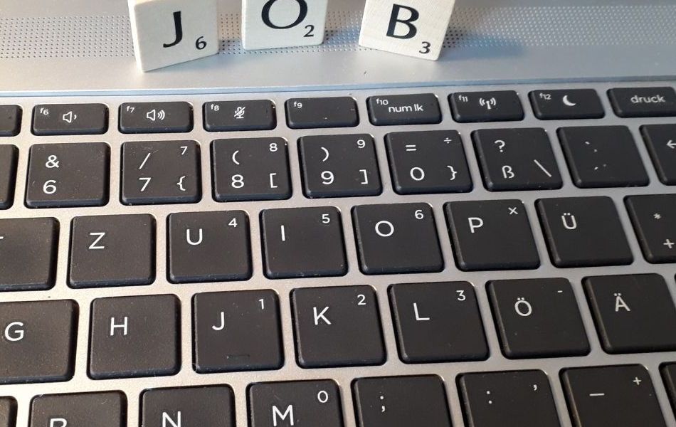 'JOB' als Holzbuchstaben auf einer Tastatur