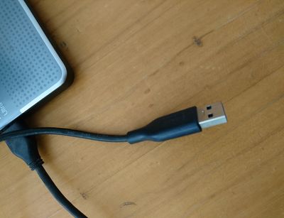 USB-Verbindungskabel einer Festplatte, die auf einem Tisch liegt.