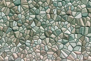 Kleine grüne Steinchen, die passend zu einem Mosaik zusammengefügt wurden.