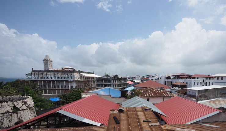 Eine Vogelperspektive auf die Dächer Sansibar Stone Town, die verschiedenste Formen von Dächern von braunen, rostigen Wellblechdächern hin zu roten, glänzenden Plastikdächern zeigt.