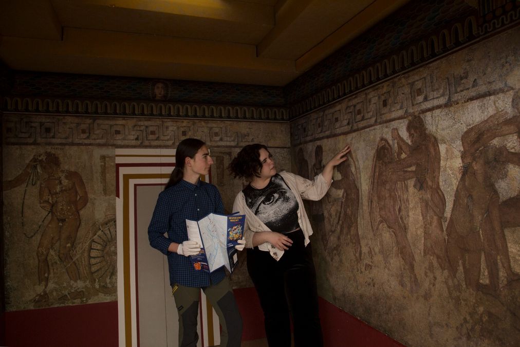 Studenten in der Reproduktion der Grabkammer Tomba Francois vor den Wandmalereien