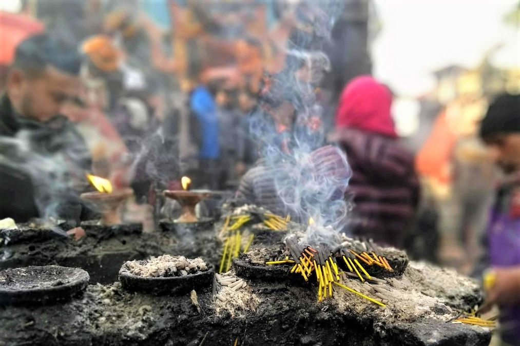 Räucherwerk brennt auf einem Stein, im Hintergrund stehen Menschen darum