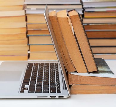 Bücher, die an einem Laptop lehnen
