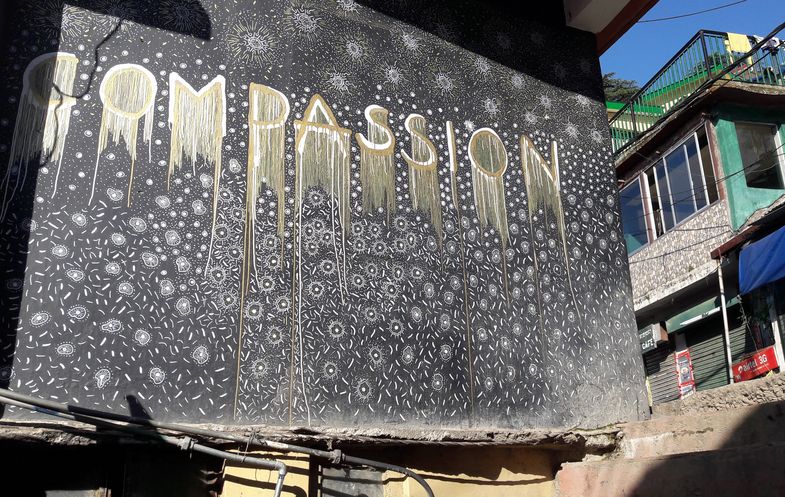 Wandgemälde in Dharamsala, Indien, welches das Wort 'Compassion', zu deutsch 'Mitgefühl' zeigt. Das Foto wurde 2017 von Dr. Frederik Schröer angefertigt.