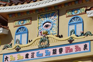 Ausschnitt eines asiatischen Tempels. An der Fassade befinden sich bunte Schriftzeichen und zahlreiche Ornamente.