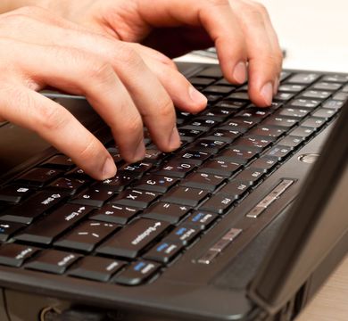 Auf dem Foto sind zwei männliche Hände zu sehen, die auf einer Laptoptastatur etwas eintippen.